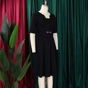 Détail d'une robe noire ligne A avec ceinture à mors doré et jupe à plis sophistiqués