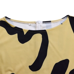 Détail d'une robe jaune moutarde avec imprimé noir abstrait et fermeture éclair blanche