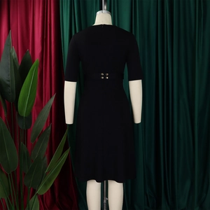 Détail de la robe noire avec boutons dorés à la taille et manches mi-longues sur mannequin