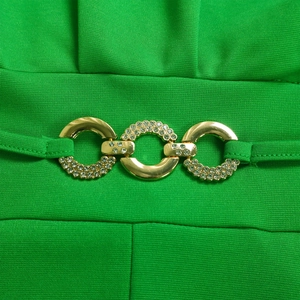 Macro detail of high-waist green jumpsuit featuring gold chain buckle with rhinestones