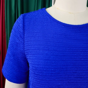 Détail du haut bleu roi à col rond montrant la texture plissée gaufrée unique