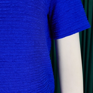 Détail d'un haut à manches courtes bleu roi avec tissu texturé gaufré et plis élégants