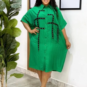 Detail of green oversized shirt dress with black ribbon straps and metallic eyelets