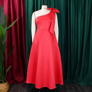 Detail of red one-shoulder evening gown featuring a large decorative bow on the shoulder