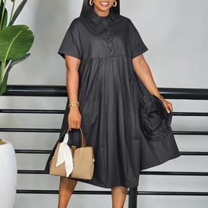 Detail view of the black short-sleeved A-line dress featuring a 3D floral accent on the hem