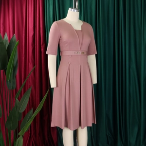 Détail de robe plissée mauve avec col en V, ceinture et boucle dorée élégante