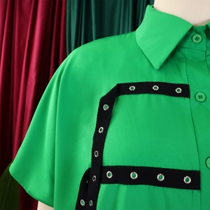 Detail of green short-sleeve shirt featuring black webbing and silver metal eyelets