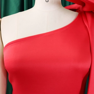 Detail of red one-shoulder dress with a large decorative bow and textured fabric