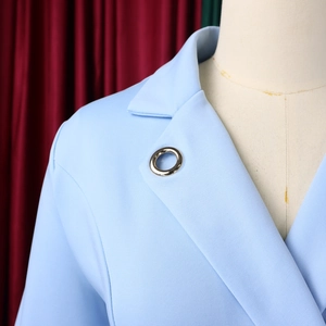 Gros plan du blazer bleu ciel avec revers classique et détail d'anneau en métal argenté