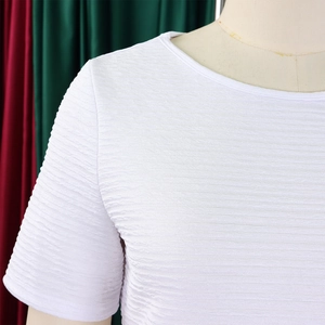 Gros plan détaillé du haut blanc à col rond montrant la texture plissée horizontale du tissu