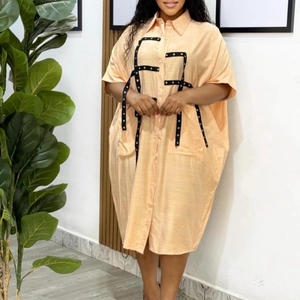 Detail of peach oversized shirt dress with black ribbon and silver eyelet trim