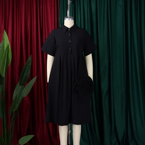 Detail of short-sleeve black dress showing lapel collar and 3D floral decoration