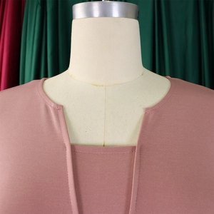 Gros plan détaillé du col en V sur une robe rose poudré montrant la texture du tricot