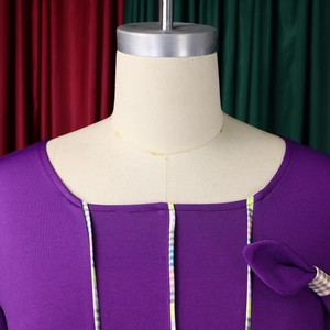 Detail of purple ribbed knit dress featuring contrast striped trim and bow accent
