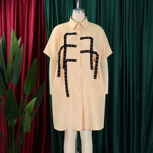Detail of apricot shirt dress featuring black strap buckles and silver eyelet accents