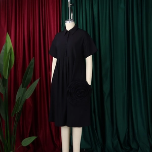 Detailed view of the 3D handcrafted floral accent on this black short sleeve shirt dress