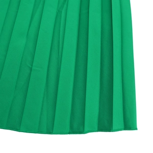 Detailed macro view of emerald green pleated fabric with fine stitching on the hemline