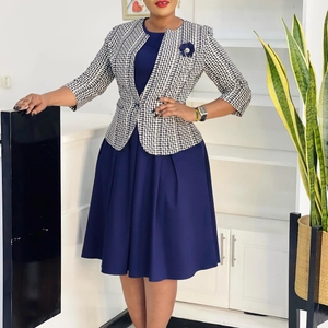 Détail d'une robe plissée bleu marine avec blazer à carreaux noir et blanc et broche