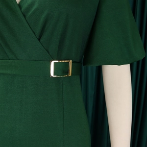 Close-up of V-neck dark green dress with textured fabric and golden waist buckle