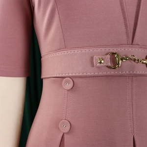 Détail macro d'une robe rose poudré élégante avec boucle mors dorée et taille structurée