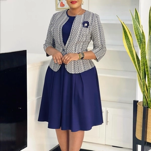 Détail de la robe bleue et veste courte à carreaux avec franges et broche chic