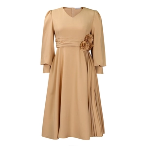 Detail view of apricot V-neck dress featuring handmade fabric flowers and pleated skirt detail