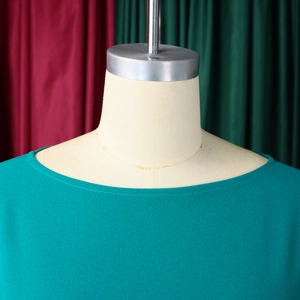 Dettaglio dell'abito a pieghe verde petrolio con scollo a barca e tessuto in chiffon
