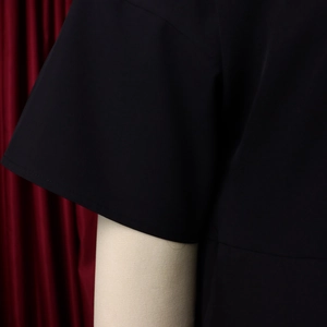 Detail of precise stitching on black short-sleeve dress sleeve and side seams