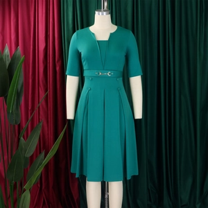 Détail d'une robe vert foncé à col en V avec ceinture à mors et jupe plissée élégante
