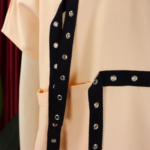 Detail view of pinkish orange dress with black trim and silver metal eyelets