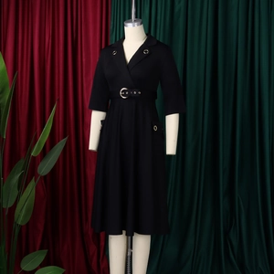Détails d'une élégante robe noire mi-longue avec col à revers et ceinture à boucle dorée