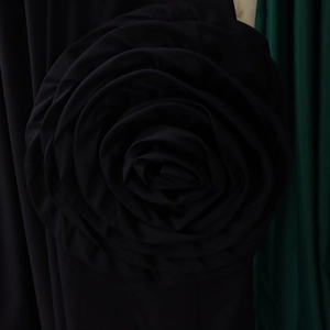 Detailed macro view of a large black fabric rose accessory with elegant layered pleated petals