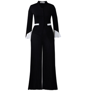 Detail of elegant black two-piece set featuring contrasting white pleated flare sleeves