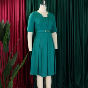 Détails de la robe vert foncé avec boucle mors dorée sur la ceinture et jupe plissée