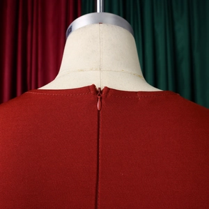 Dettaglio macro dello scollo posteriore di un abito rosso con cerniera invisibile e trama