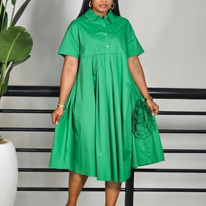 Detailed close-up of a green A-line shirt dress with 3D floral accent and pleated hem