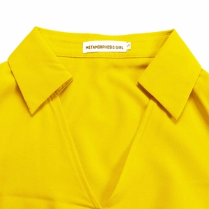 Detail of the V-neck and collar on this bright yellow long-sleeved pleated dress