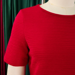 Détail macro du haut rouge à col rond montrant la texture unique du tissu gaufré sur mannequin