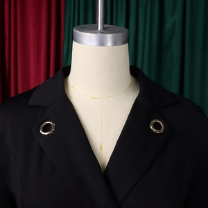 Détail d'une robe noire élégante montrant un col à revers avec anneaux dorés en métal