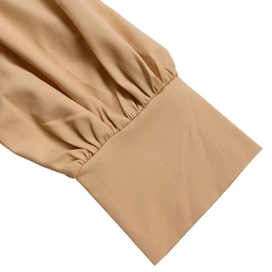 Detailed macro shot of elegant pleated chiffon sleeves on a beige A-line dress