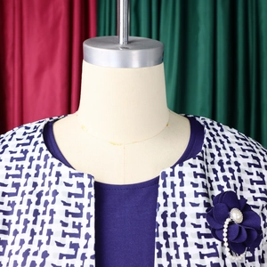 Détail d'un gilet à imprimé géométrique avec broche fleurie en perles et haut marine