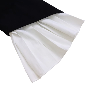 Detail of flared sleeves featuring contrasting black and white pleated fabric textures