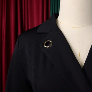 Détail d'un blazer noir avec broche anneau doré sur un mannequin de couture