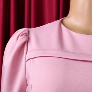 Dettaglio delle maniche a sbuffo rosa e del tessuto strutturato di questo abito a girocollo