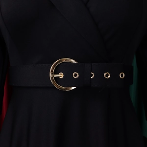 Détail d'une robe noire élégante montrant une ceinture à boucle dorée ronde et œillets