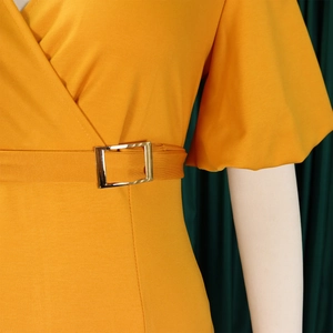 Detail of yellow V-neck dress featuring puff sleeves and a gold metal buckle belt