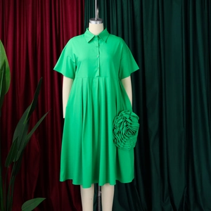 Detail of emerald green short sleeve dress with large 3D fabric rose decoration