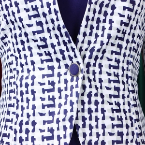 Détail du tissu à imprimé géométrique bleu et blanc avec un bouton bleu marine bordé d'argent