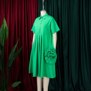 Detail of green A-line dress featuring a large 3D fabric rose and buttoned lapel