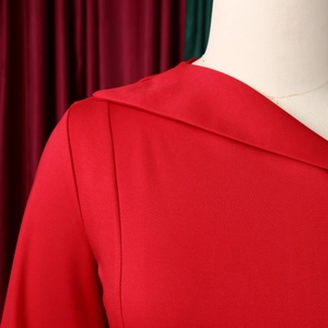 Close-up of elegant asymmetric red dress neckline showing refined overlapping lapel texture